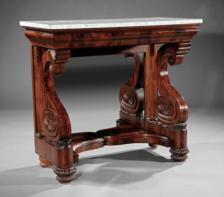 An antique mahogany console table with a white marble top and ornate, curved legs featuring carved rosettes, set against a plain gray background.