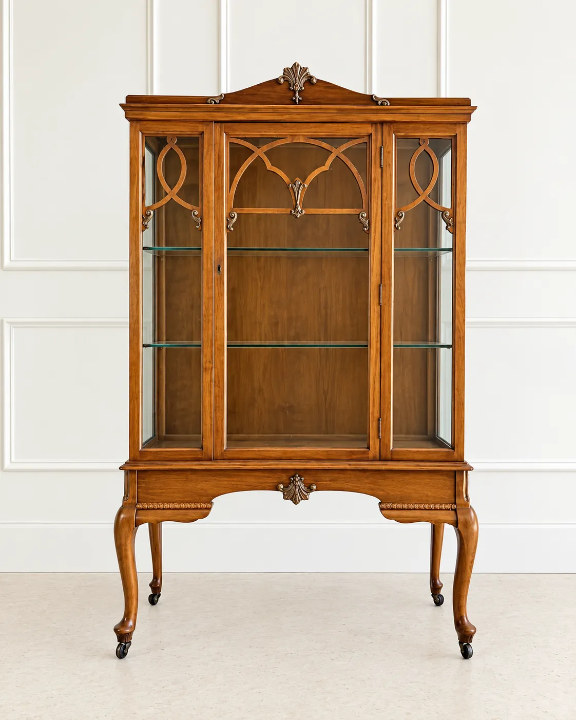 A classic Sheesham Display Cabinet with glass doors, intricate wooden arches, and elegant cabriole legs, set against a white paneled wall.